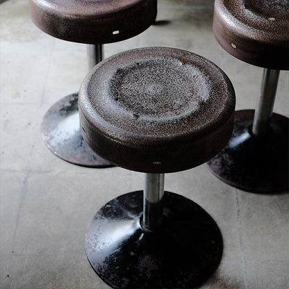 A swivel stool with rusty iron legs