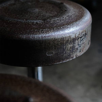 A swivel stool with rusty iron legs