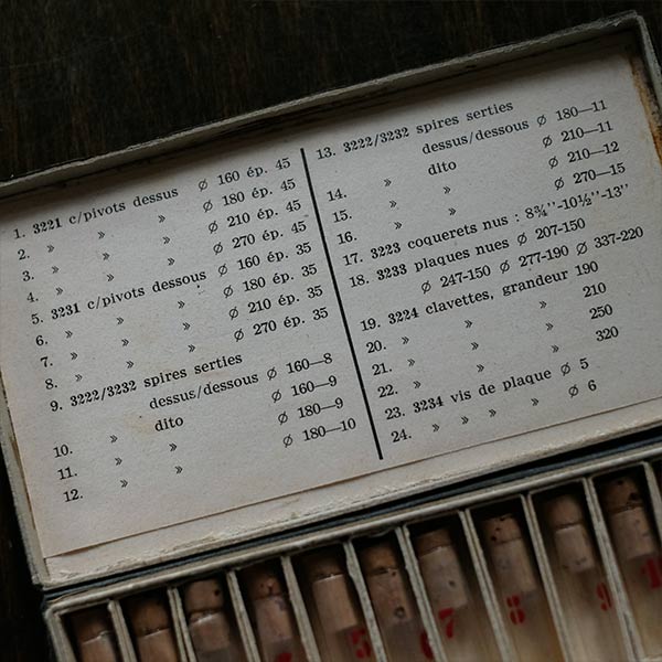 A set of small jars containing mechanical watch parts