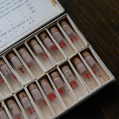 A set of small jars containing mechanical watch parts